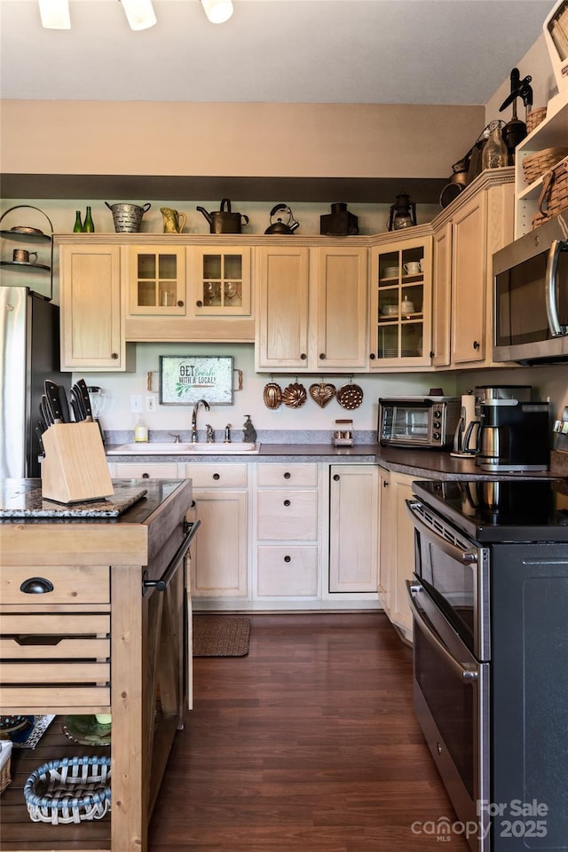 kitchen featuring stainless steel appliances, dark wood-style flooring, a sink, and glass insert cabinets