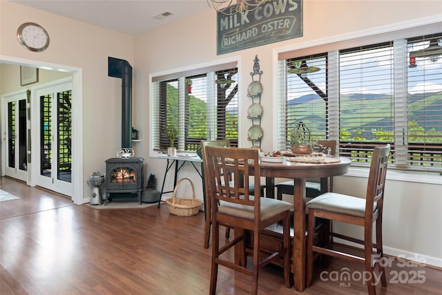 dining area featuring a wood stove, baseboards, and wood finished floors