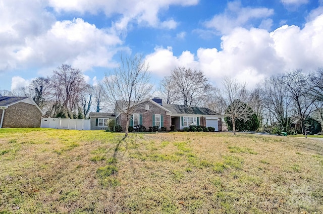 ranch-style home featuring brick siding, a front yard, fence, and a garage