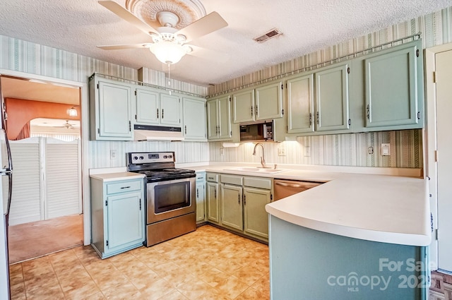 kitchen with visible vents, electric stove, under cabinet range hood, a sink, and wallpapered walls