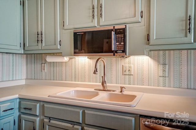 kitchen featuring stainless steel dishwasher, light countertops, black microwave, and a sink