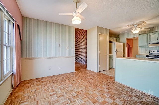 kitchen featuring green cabinets, freestanding refrigerator, electric range, a textured ceiling, and a ceiling fan