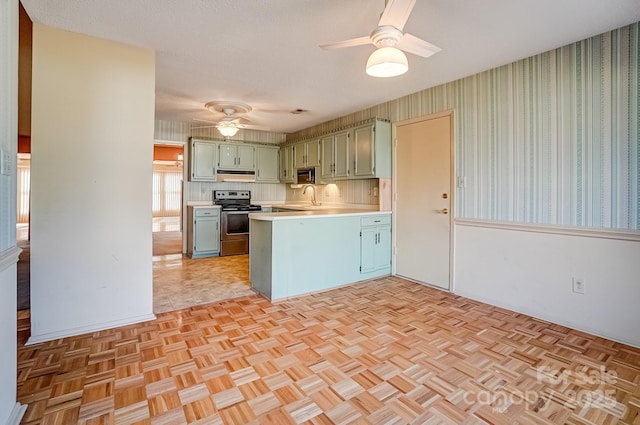 kitchen featuring wallpapered walls, a peninsula, ceiling fan, stainless steel appliances, and light countertops