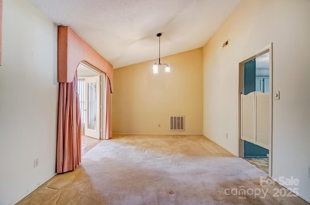 empty room featuring lofted ceiling, visible vents, and carpet floors