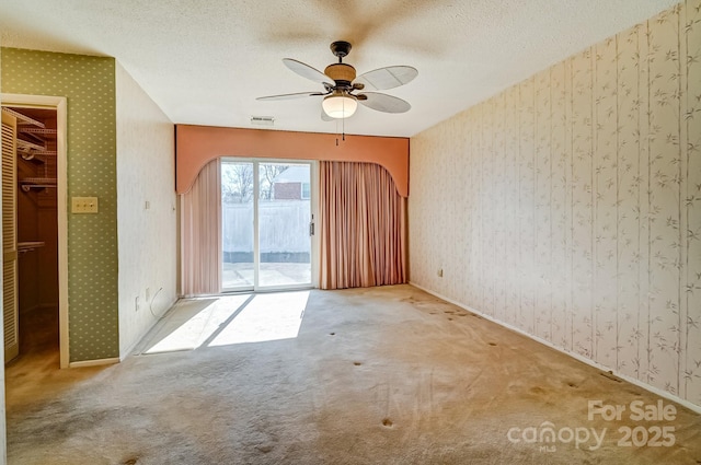 spare room with visible vents, wallpapered walls, and carpet floors