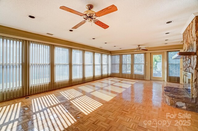 unfurnished sunroom featuring visible vents, a fireplace, and ceiling fan