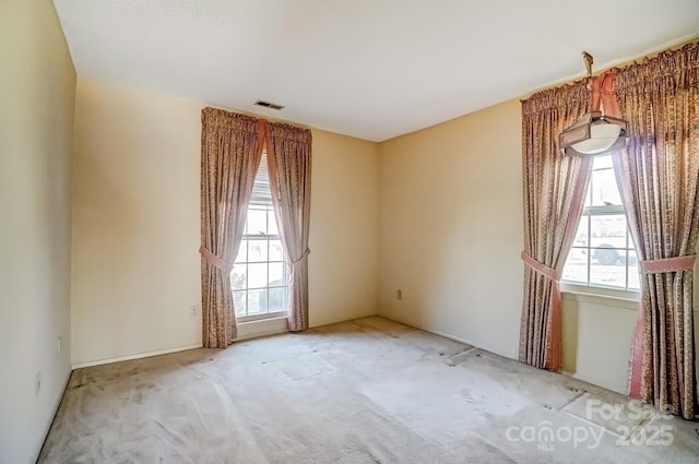 carpeted spare room with visible vents and a healthy amount of sunlight