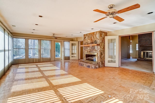 unfurnished living room featuring visible vents, a ceiling fan, and a fireplace