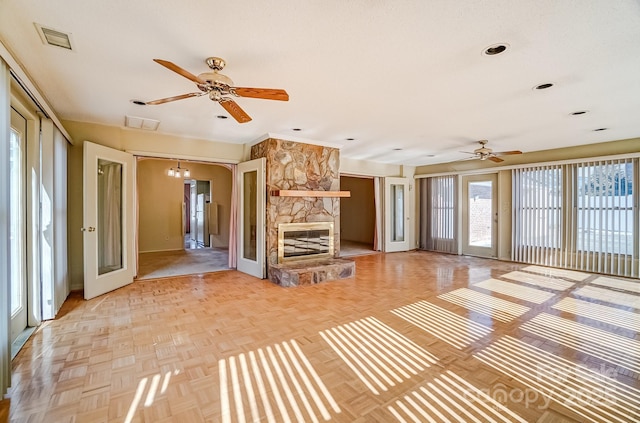 unfurnished living room with visible vents, a fireplace, baseboards, and a ceiling fan