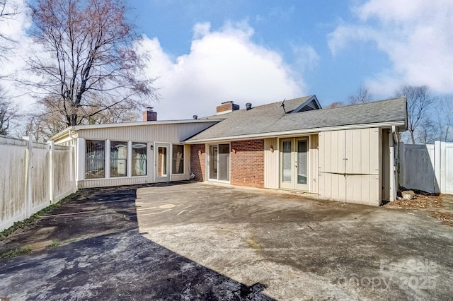 back of house with a fenced backyard, a chimney, french doors, a patio area, and brick siding