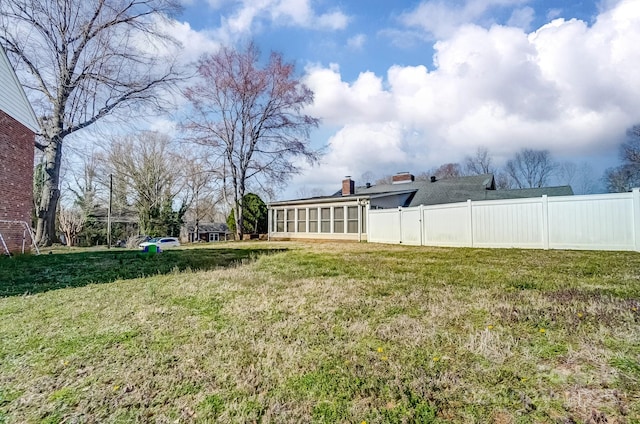 view of yard with a sunroom and fence