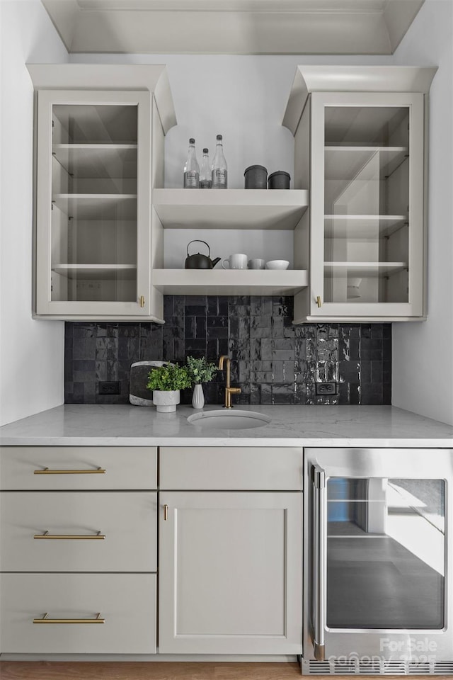 bar with sink, backsplash, white cabinets, and beverage cooler