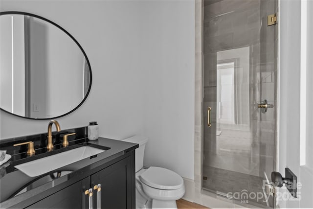 bathroom with toilet, vanity, and a shower with shower door