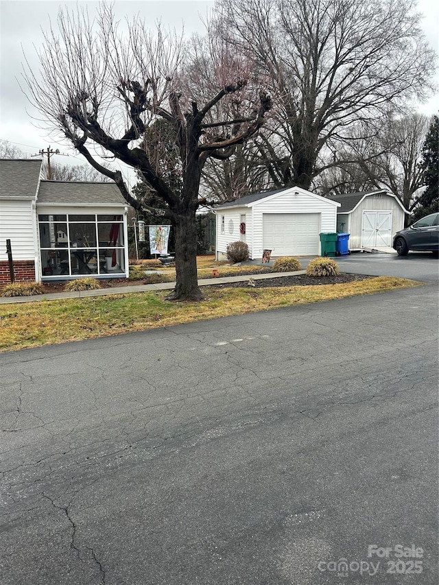 view of front of home featuring a storage shed, a garage, and a sunroom