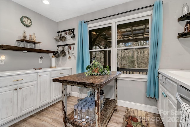 interior space featuring light wood finished floors, white cabinets, baseboards, and open shelves