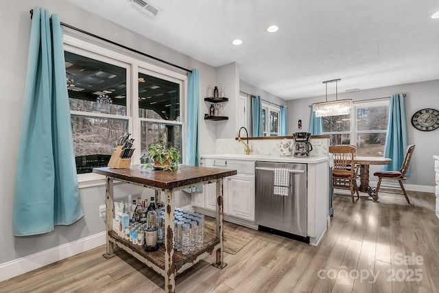 kitchen with light wood-type flooring, visible vents, stainless steel dishwasher, and a sink