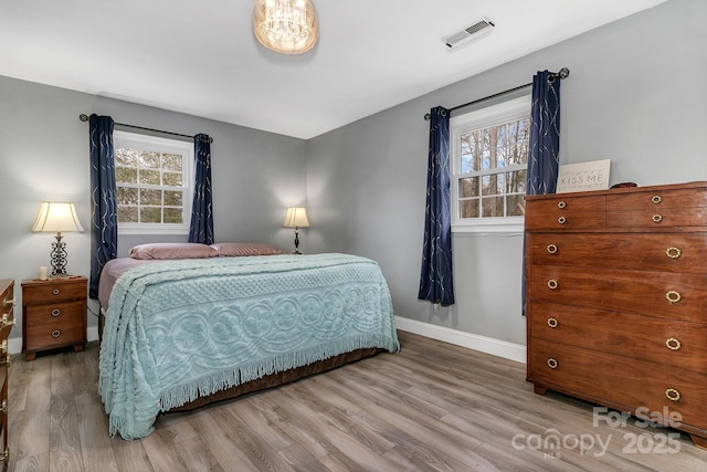 bedroom featuring multiple windows, wood finished floors, and visible vents