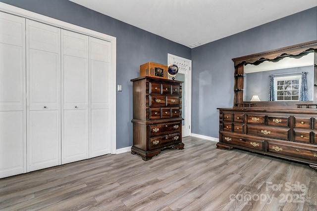 bedroom with a closet, baseboards, and light wood-style floors