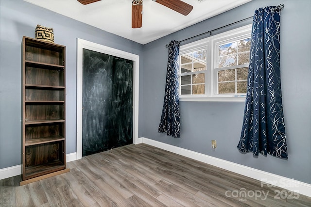 unfurnished room with ceiling fan, baseboards, and wood finished floors