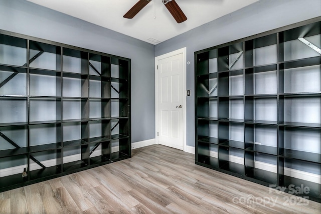 spare room featuring baseboards, wood finished floors, and a ceiling fan