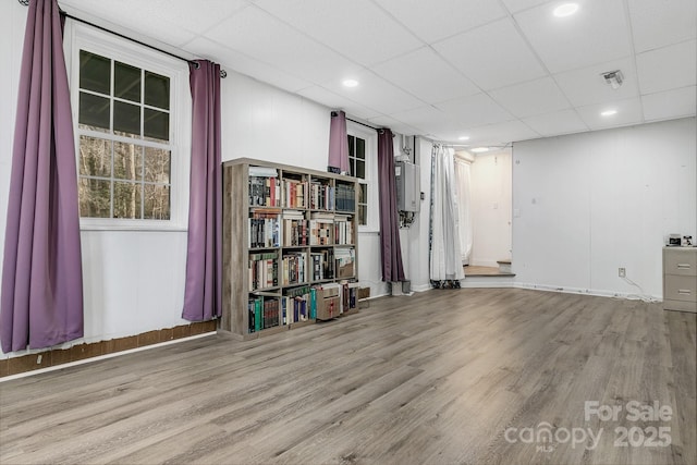 finished basement with visible vents, a paneled ceiling, baseboards, and wood finished floors