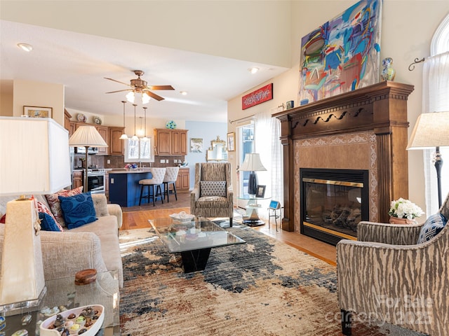 living room featuring ceiling fan and a tile fireplace