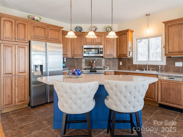 kitchen with a breakfast bar, sink, a center island, hanging light fixtures, and appliances with stainless steel finishes