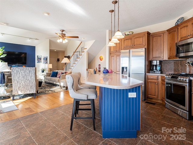 kitchen with a breakfast bar, hanging light fixtures, a kitchen island, stainless steel appliances, and backsplash