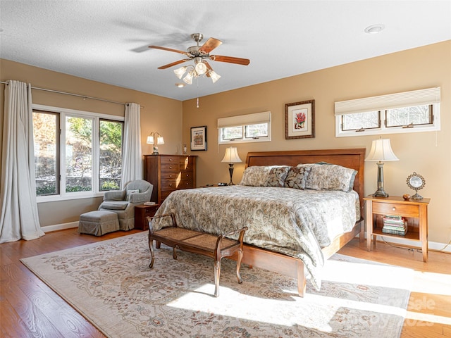 bedroom with multiple windows, a textured ceiling, light hardwood / wood-style flooring, and ceiling fan