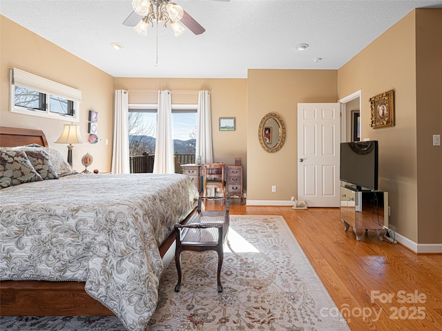 bedroom with access to exterior, ceiling fan, a textured ceiling, and light wood-type flooring