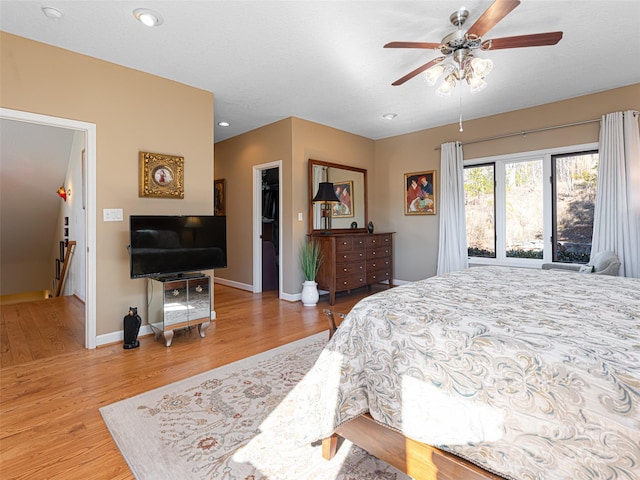 bedroom featuring ceiling fan, light hardwood / wood-style floors, and a walk in closet