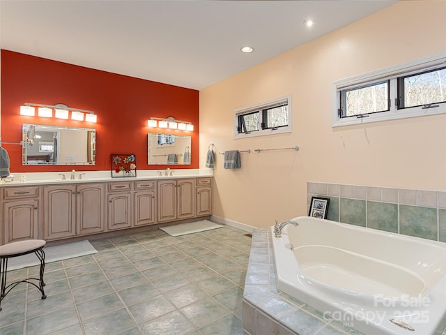 bathroom with tile patterned floors, vanity, and tiled bath