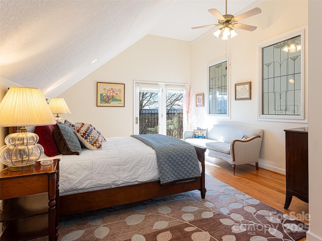 bedroom with hardwood / wood-style flooring, lofted ceiling, a textured ceiling, and access to outside