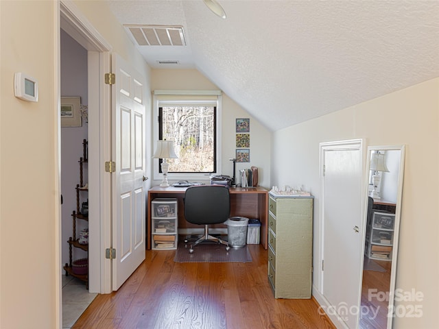 home office featuring wood-type flooring, vaulted ceiling, and a textured ceiling