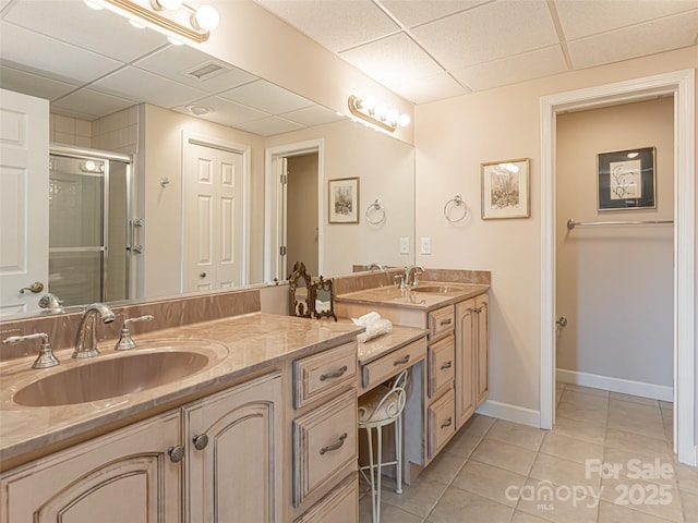 bathroom with a shower with door, vanity, a drop ceiling, and tile patterned floors