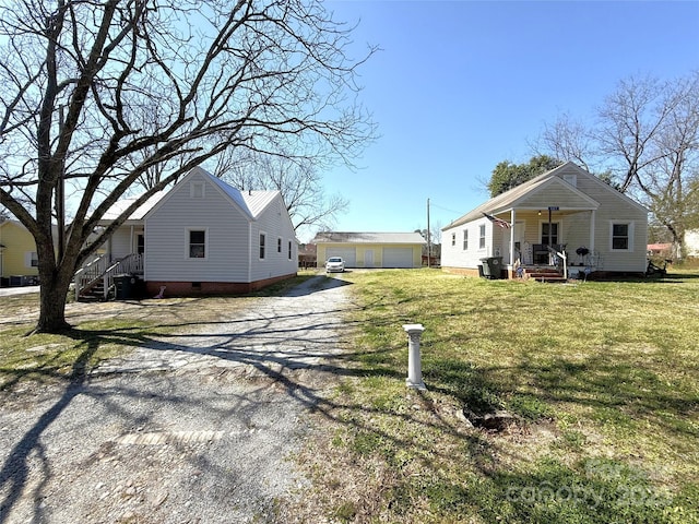 exterior space featuring crawl space, a porch, a lawn, a garage, and an outbuilding