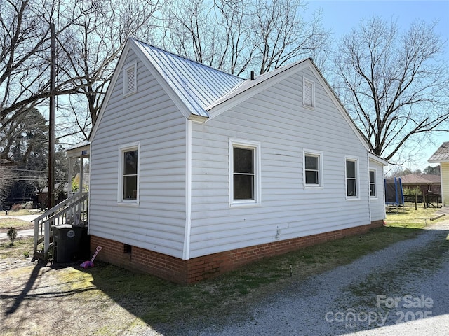 view of home's exterior with central AC unit, metal roof, driveway, and crawl space