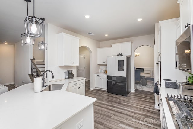 kitchen featuring arched walkways, white cabinets, hanging light fixtures, light countertops, and smart refrigerator