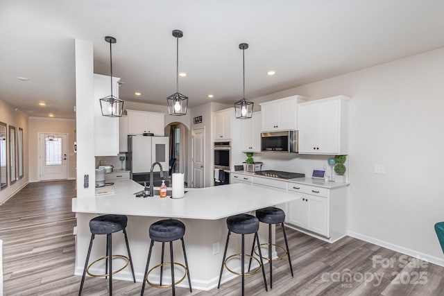 kitchen featuring light countertops, appliances with stainless steel finishes, a breakfast bar, and white cabinetry