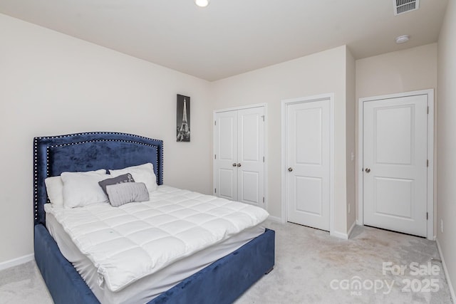 bedroom featuring light colored carpet, visible vents, baseboards, and two closets