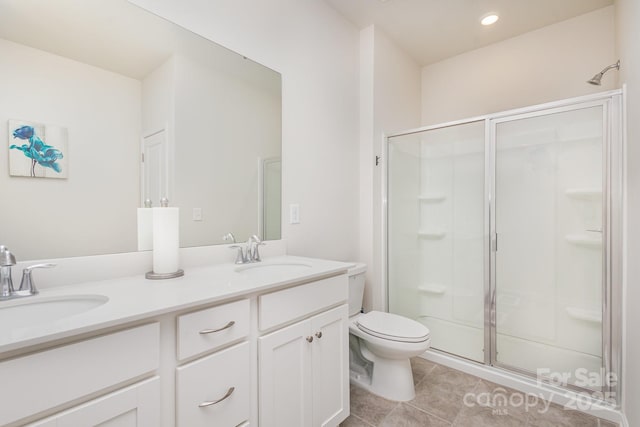 bathroom with double vanity, a shower stall, toilet, and a sink