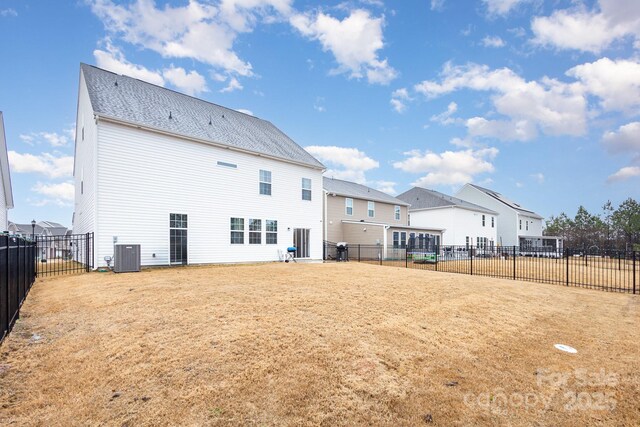 rear view of property featuring a fenced backyard and central AC