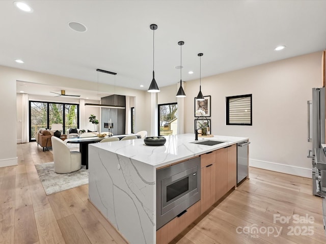 kitchen featuring light wood-style flooring, stainless steel appliances, a sink, a large island, and modern cabinets