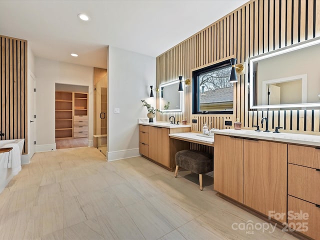 bathroom with a shower stall, two vanities, recessed lighting, and baseboards