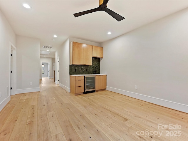 kitchen with visible vents, backsplash, light brown cabinets, wine cooler, and light wood-type flooring