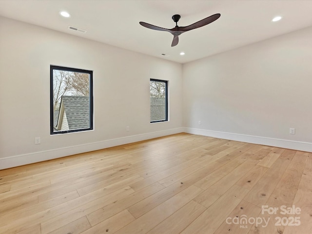 empty room featuring visible vents, light wood-type flooring, and baseboards