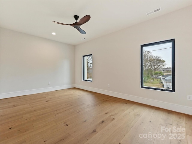 spare room with light wood-type flooring, baseboards, visible vents, and a ceiling fan