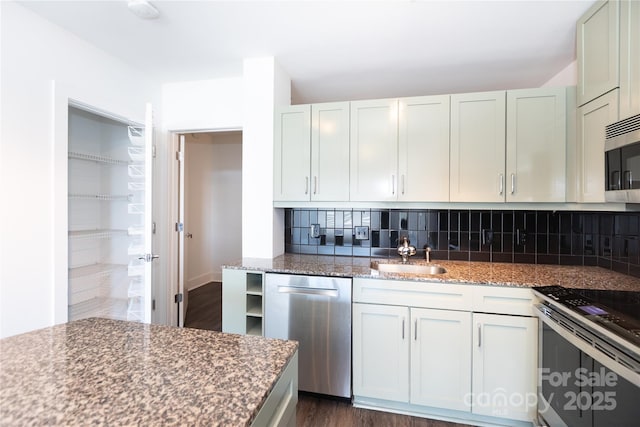 kitchen with decorative backsplash, appliances with stainless steel finishes, stone countertops, and a sink