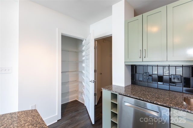 kitchen featuring dark stone countertops, dark wood-style flooring, green cabinets, stainless steel dishwasher, and tasteful backsplash