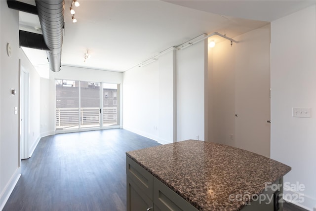 kitchen featuring dark stone counters, baseboards, dark wood finished floors, and a center island